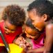 Three young children sharing a tablet together outdoors