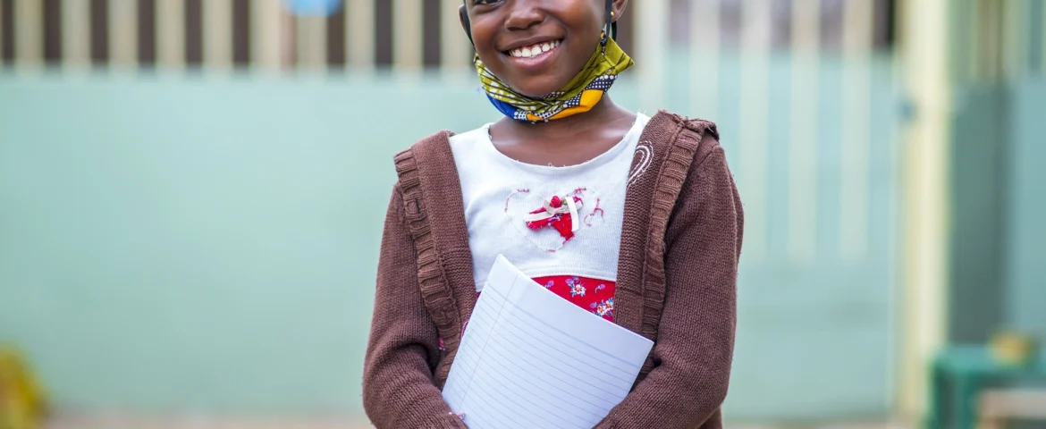 Smiling schoolgirl holding her exercise book, supported by Oloowere Foundation tuition assistance